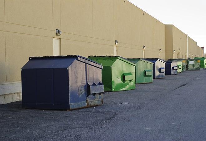 a construction worker empties a wheelbarrow of waste into the dumpster in Coral Springs